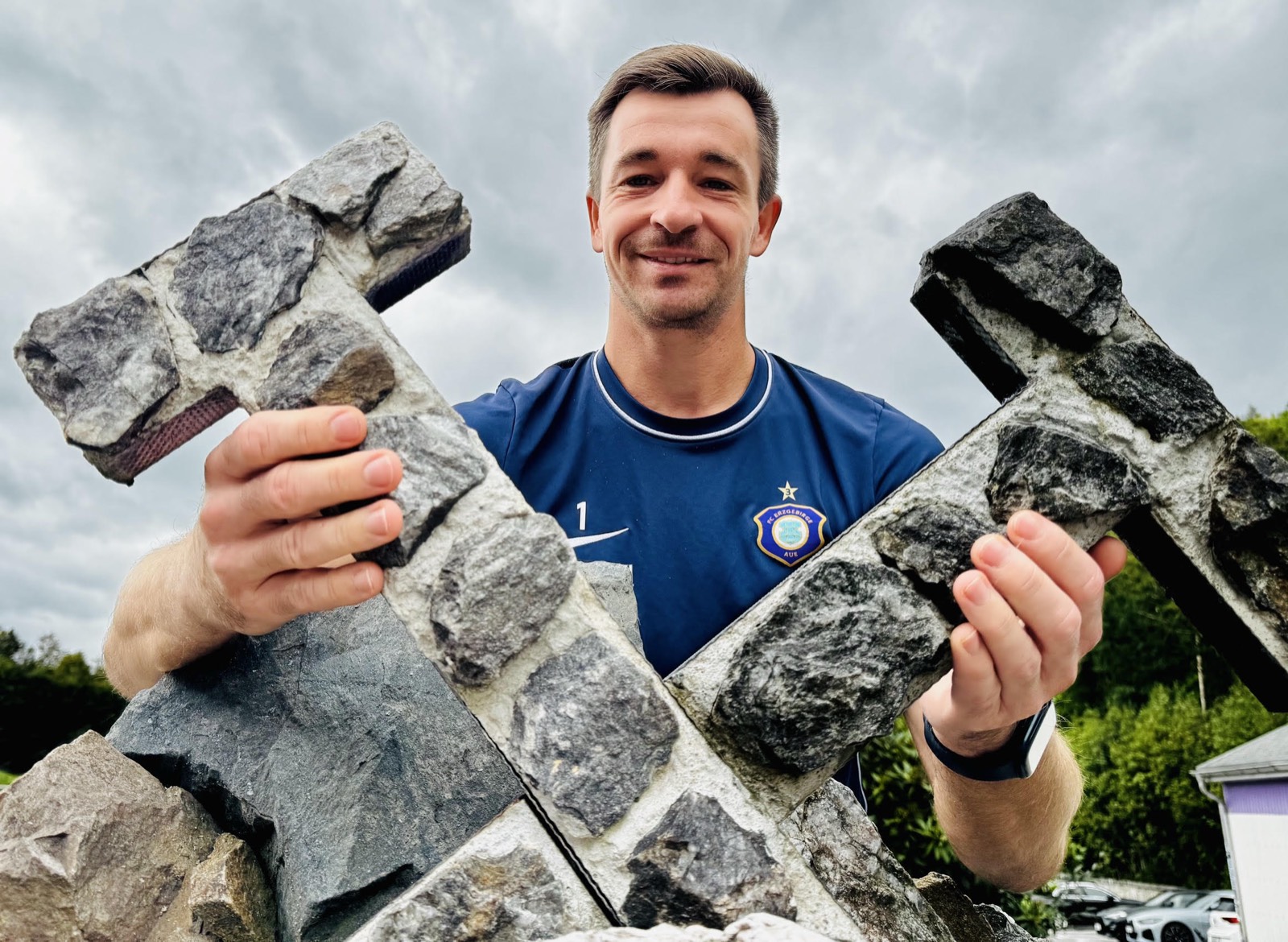 Martin Männel im Trikot des FC Erzgebirge Aue hält zwei steinerne Hämmer vor sich